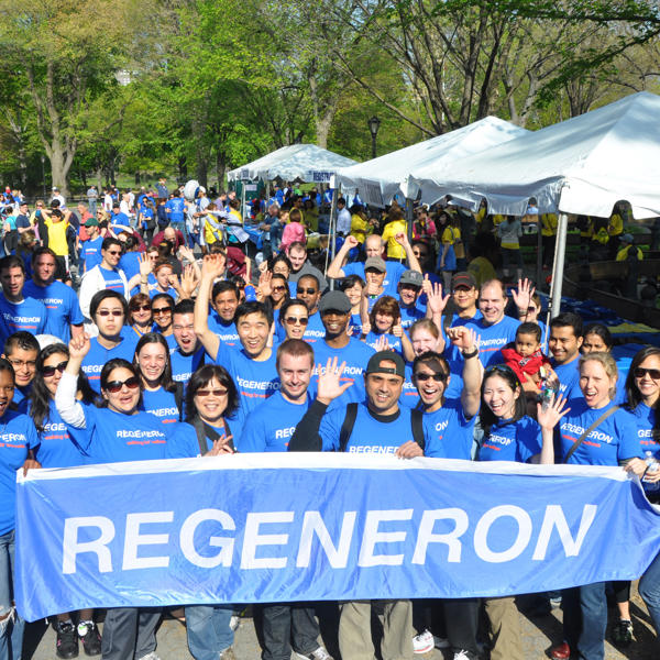 A group of people in blue shirts holding a Regeneron banner