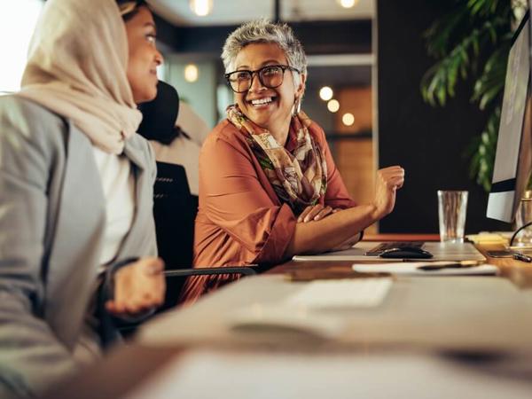 机に座る女性と笑顔の女性