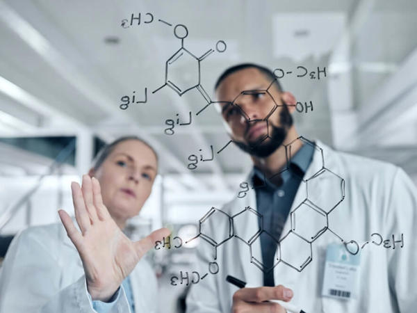 白衣を着た男女がガラス板に文字を書く